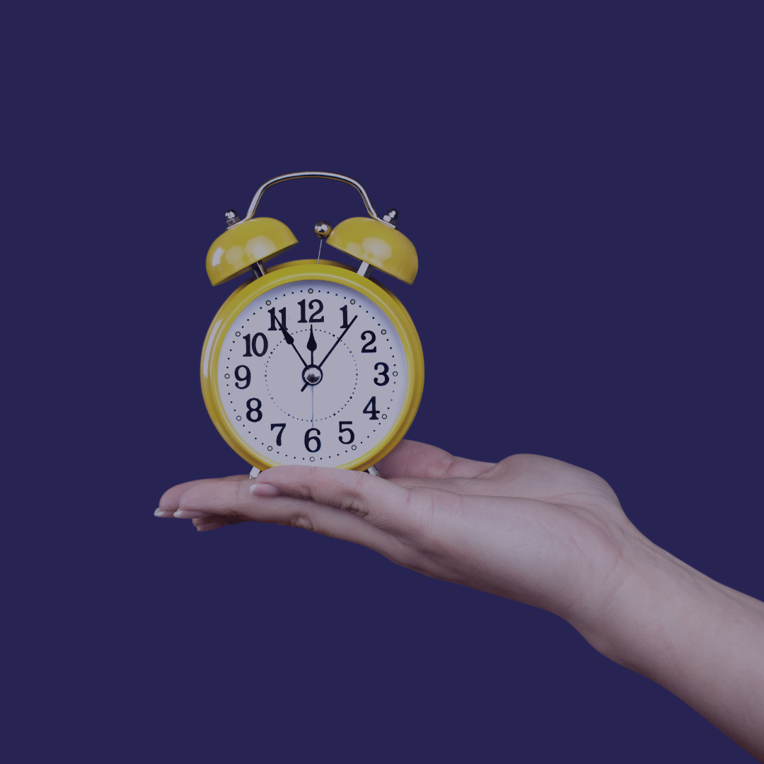A yellow alarm clock sits on top of a woman's hand