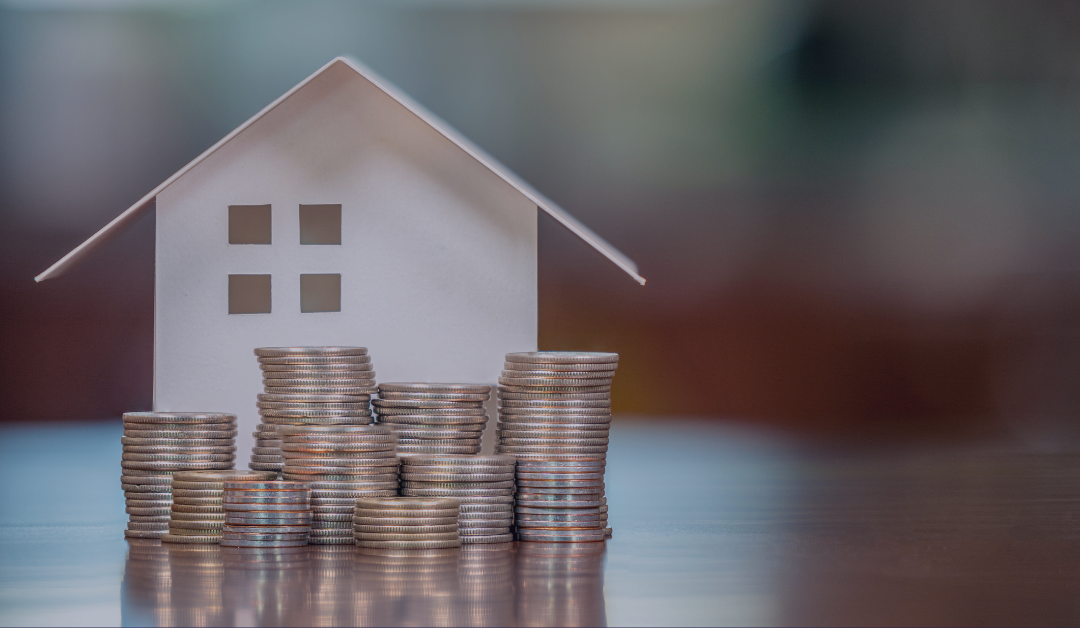 A toy house stands behind several stacks of coins