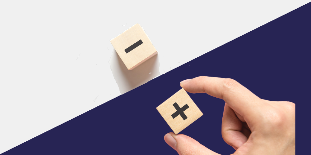 Fingers hold a positive dice, but a negative one is also on the table